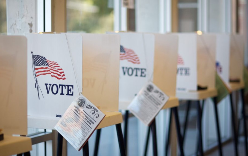 Row of voting booths with VOTE signs in a polling place